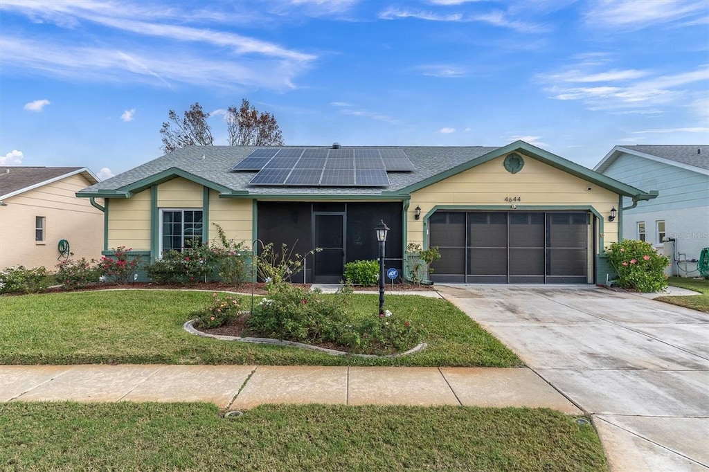 ranch-style home with solar panels, a garage, and a front lawn