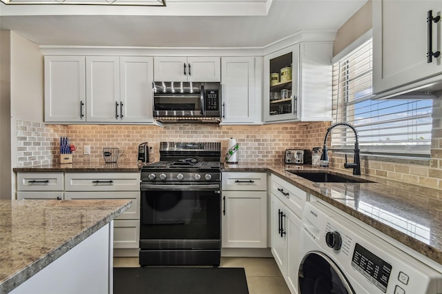 kitchen featuring white cabinets, gas stove, washer / dryer, and sink