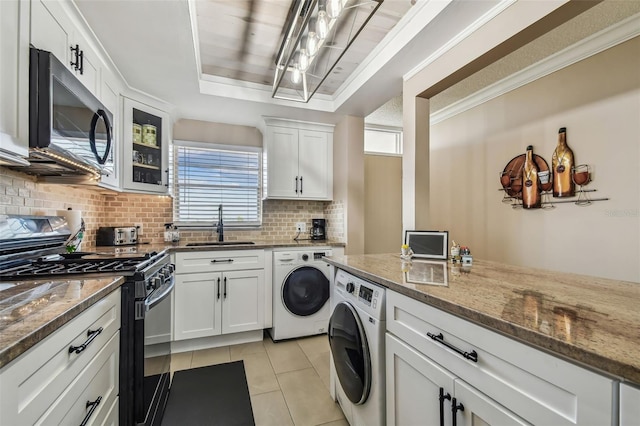 interior space featuring dark stone countertops, washer / clothes dryer, appliances with stainless steel finishes, and white cabinets