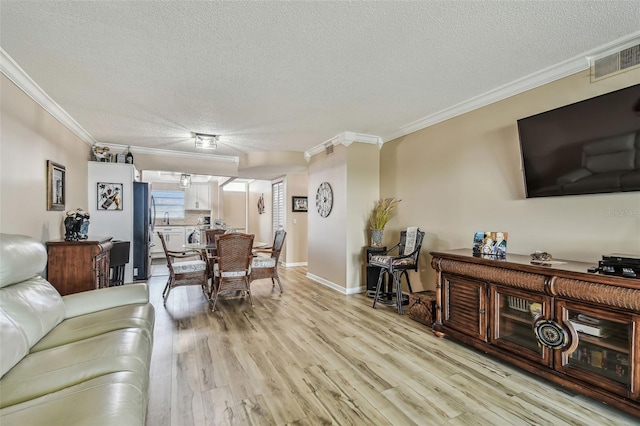 living room featuring a textured ceiling, light hardwood / wood-style flooring, and crown molding