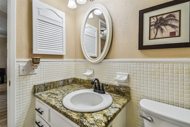 bathroom with tile walls, vanity, and toilet