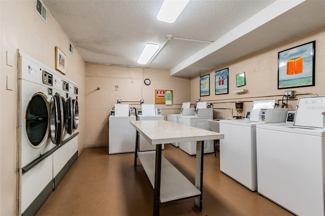 clothes washing area with a textured ceiling and separate washer and dryer