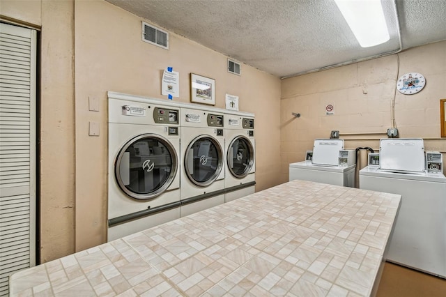 laundry area with separate washer and dryer and a textured ceiling