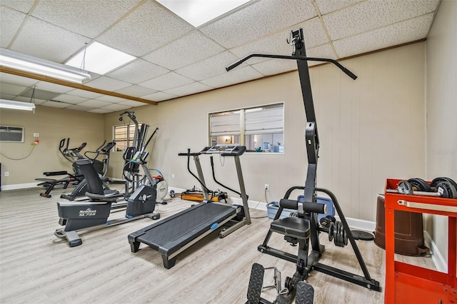 workout area with a drop ceiling, a wall unit AC, plenty of natural light, and hardwood / wood-style floors