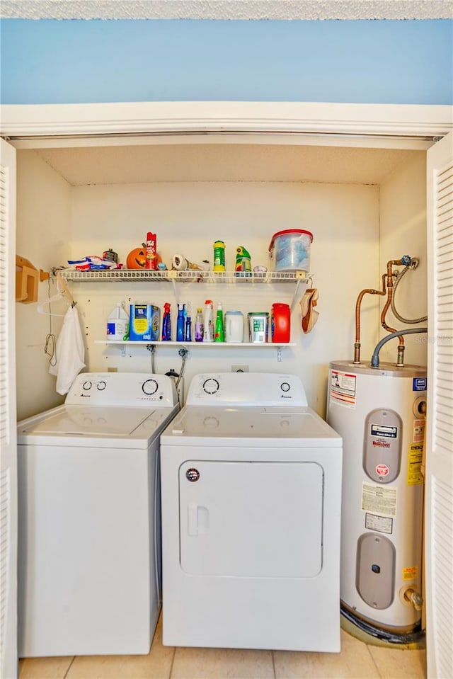 washroom with washing machine and clothes dryer, electric water heater, and light tile patterned flooring