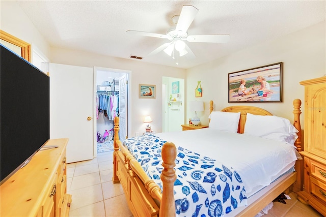 bedroom featuring ceiling fan, a spacious closet, a textured ceiling, a closet, and light tile patterned floors