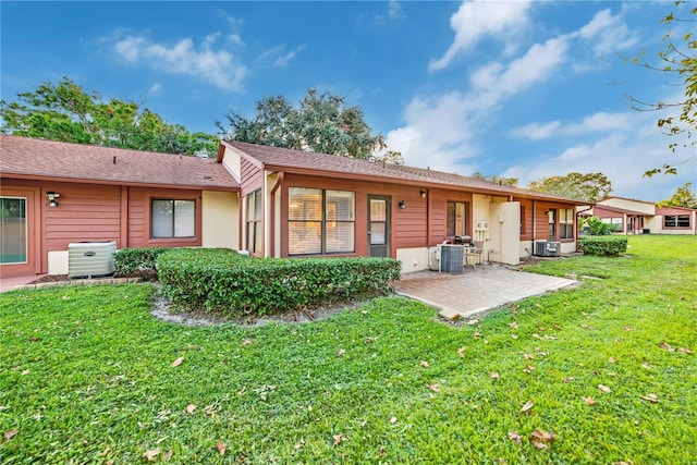 back of property with a lawn, central AC unit, and a patio