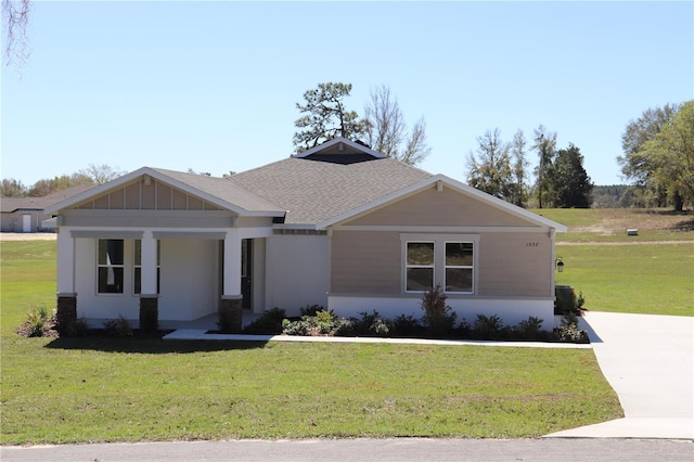 view of front of house featuring a shingled roof, a front lawn, and board and batten siding