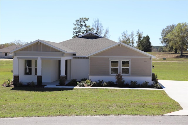 craftsman-style home with board and batten siding, a front yard, and roof with shingles