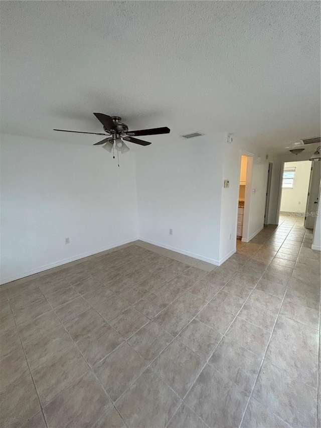 empty room with visible vents, baseboards, ceiling fan, a textured ceiling, and light tile patterned flooring