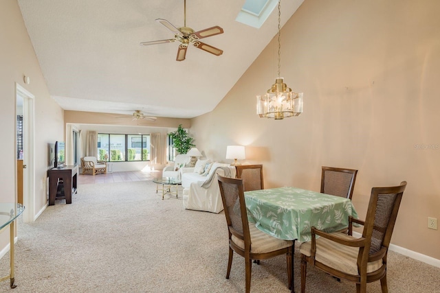 carpeted dining space featuring a skylight, ceiling fan with notable chandelier, and high vaulted ceiling