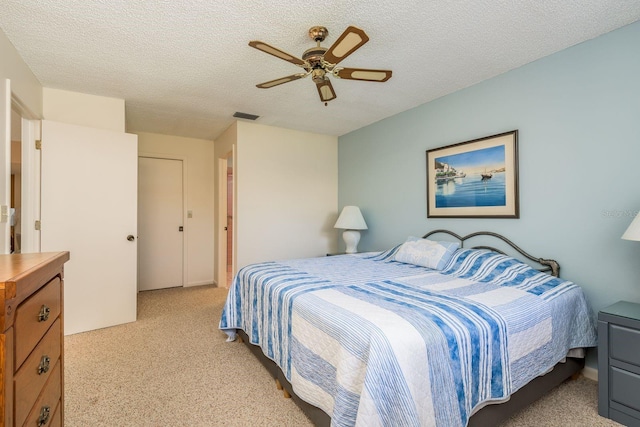 carpeted bedroom with ceiling fan and a textured ceiling