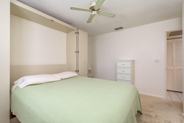 bedroom featuring light carpet, a closet, ceiling fan, and a textured ceiling