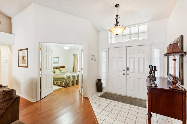 entryway with a towering ceiling, light hardwood / wood-style flooring, and ceiling fan