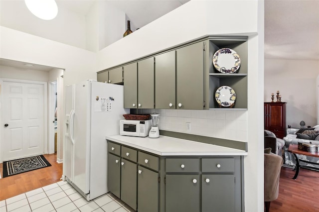 kitchen with high vaulted ceiling, white appliances, light hardwood / wood-style floors, and backsplash