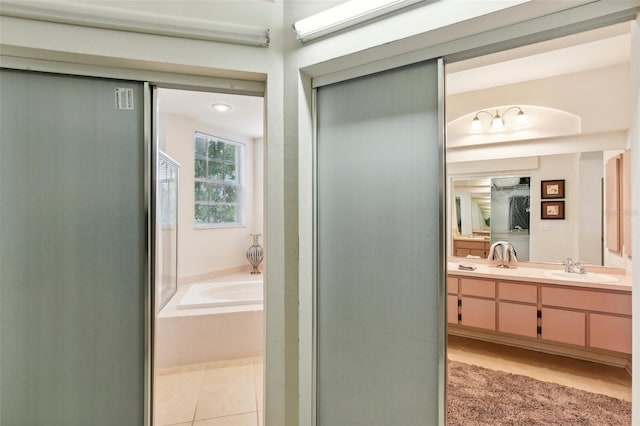 bathroom featuring tile patterned floors, tiled tub, and vanity