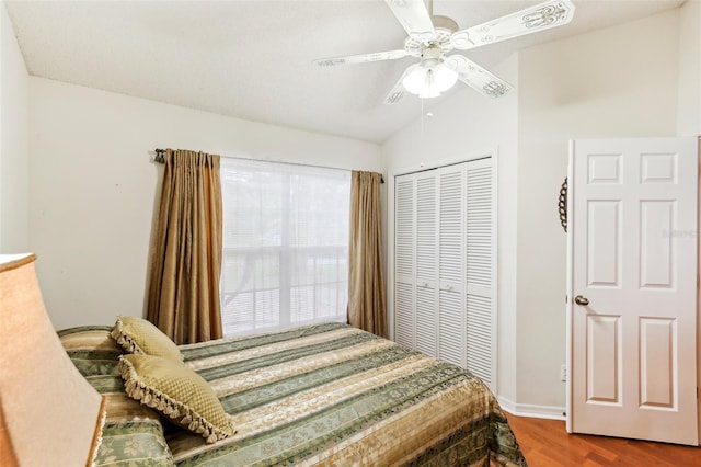 bedroom with ceiling fan, hardwood / wood-style flooring, a closet, and lofted ceiling