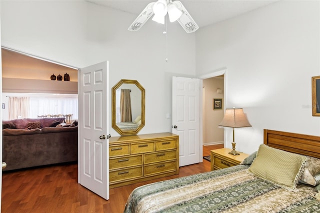 bedroom with ceiling fan, dark hardwood / wood-style floors, and a towering ceiling