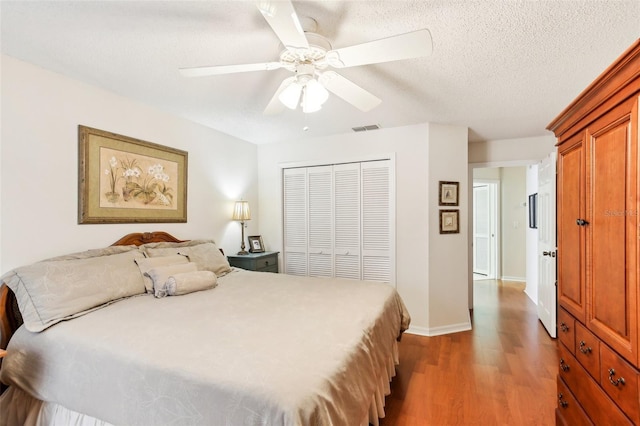 bedroom featuring ceiling fan, a textured ceiling, a closet, and wood-type flooring