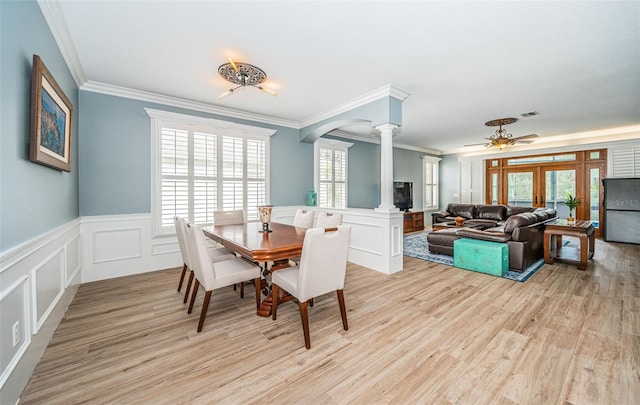 dining room featuring light hardwood / wood-style flooring, a healthy amount of sunlight, and ornate columns