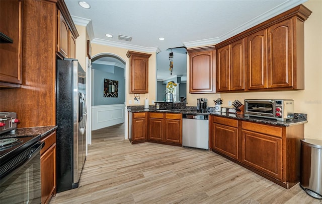 kitchen with light hardwood / wood-style floors, crown molding, appliances with stainless steel finishes, and dark stone counters