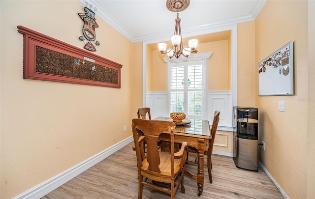 dining room with ornamental molding, light hardwood / wood-style flooring, and an inviting chandelier