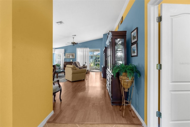 corridor with hardwood / wood-style flooring and vaulted ceiling