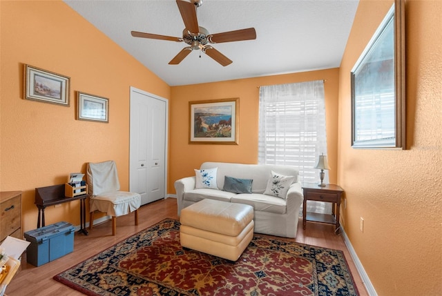 living area featuring wood-type flooring, vaulted ceiling, and ceiling fan