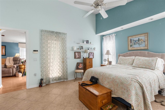 bedroom with ceiling fan, light tile patterned floors, and a towering ceiling