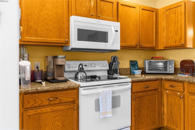 kitchen featuring dark stone countertops and white appliances