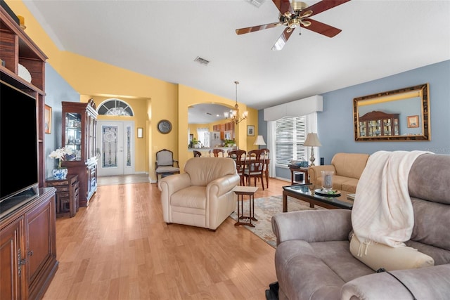 living room featuring ceiling fan with notable chandelier, light hardwood / wood-style floors, and vaulted ceiling