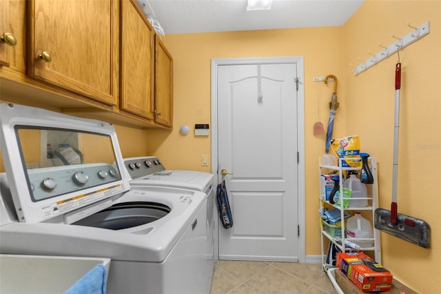 laundry room featuring washing machine and clothes dryer, sink, light tile patterned floors, and cabinets