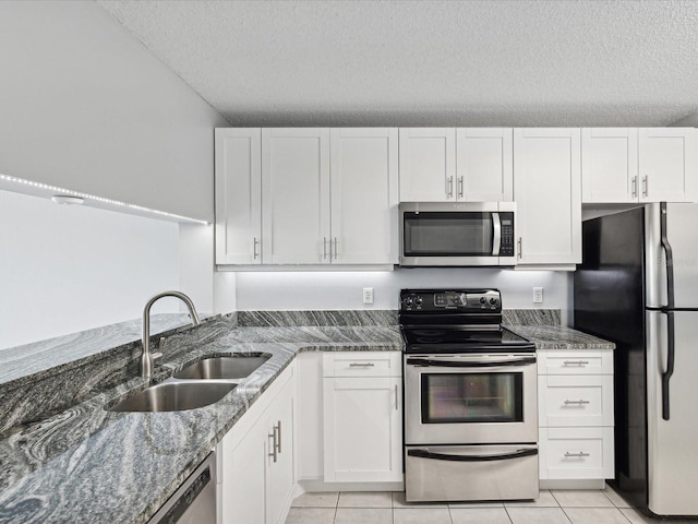 kitchen featuring dark stone countertops, sink, white cabinets, appliances with stainless steel finishes, and a textured ceiling