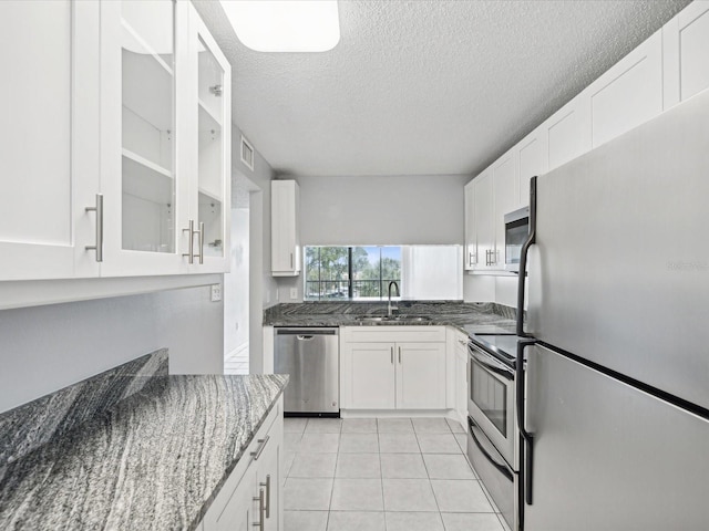 kitchen with white cabinets, stainless steel appliances, sink, and dark stone counters