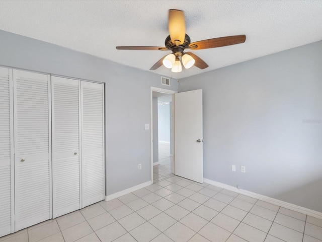 unfurnished bedroom with a closet, light tile patterned floors, a textured ceiling, and ceiling fan