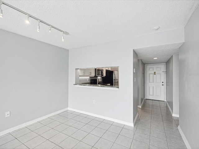 tiled empty room featuring a textured ceiling