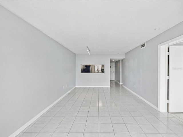 spare room with a textured ceiling and light tile patterned floors