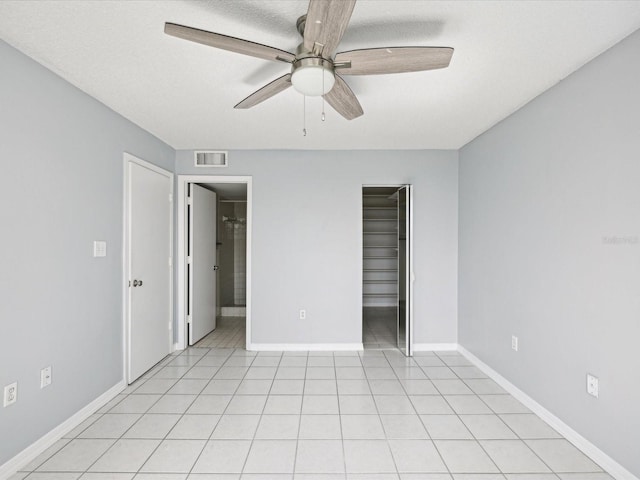 unfurnished bedroom featuring light tile patterned flooring, ceiling fan, a closet, and a textured ceiling