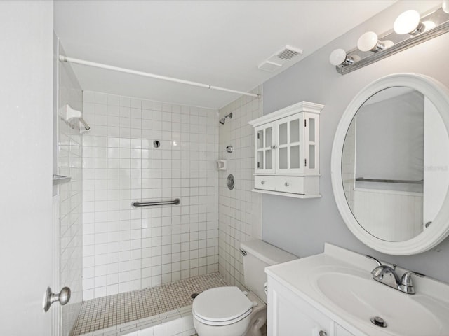 bathroom with vanity, tiled shower, and toilet