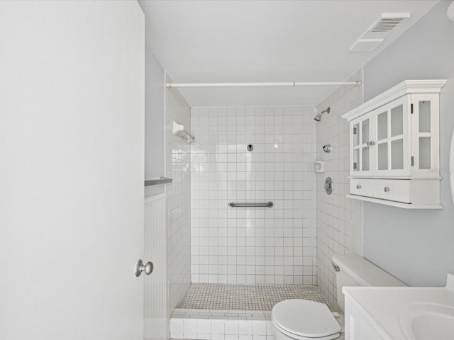 bathroom featuring vanity, toilet, and tiled shower