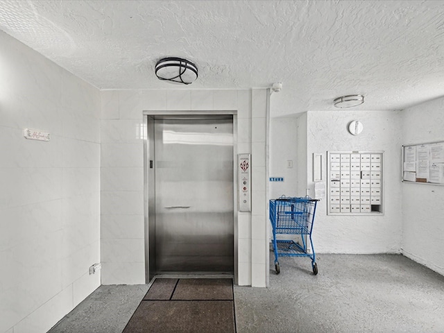 bathroom with elevator, a mail area, and a textured ceiling