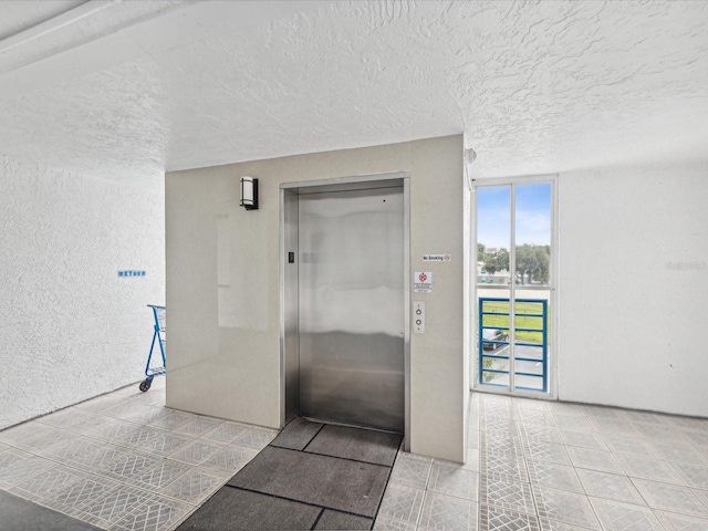 corridor with elevator and a textured ceiling