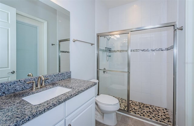 bathroom with toilet, vanity, tile patterned floors, and an enclosed shower