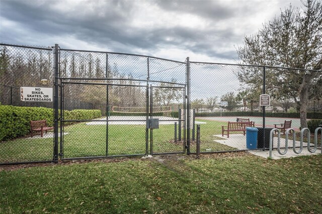 view of property's community featuring a lawn and tennis court