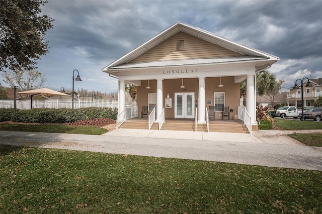 exterior space featuring covered porch, french doors, and a front lawn