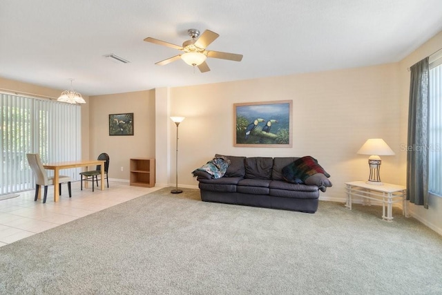 living room featuring ceiling fan with notable chandelier and light colored carpet