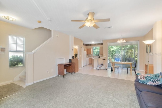 living room featuring ceiling fan with notable chandelier and light colored carpet