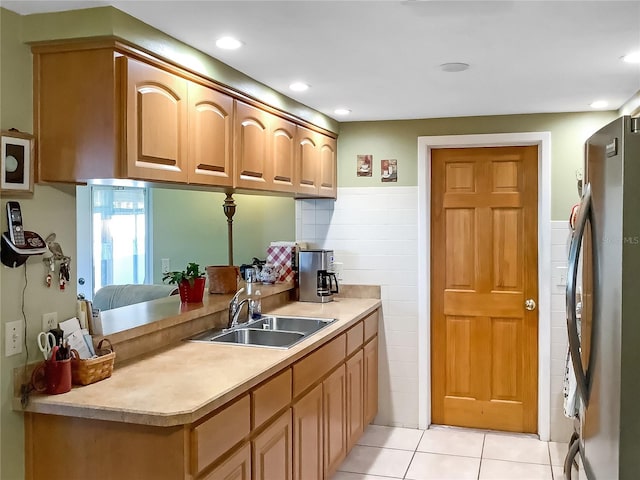 kitchen featuring stainless steel refrigerator, sink, and light tile patterned floors