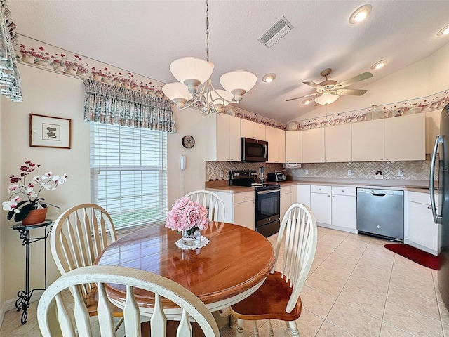 tiled dining area featuring a textured ceiling, ceiling fan with notable chandelier, and vaulted ceiling