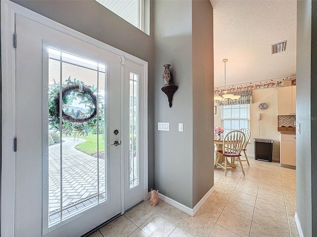 tiled foyer entrance with a notable chandelier and a textured ceiling